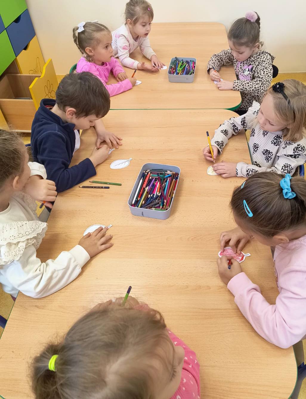 dzieci siedzą przy stole i rozwiązują zadania